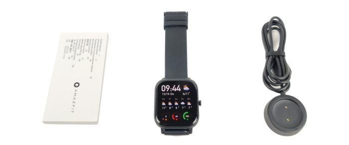 El alcance de entrega de Amazfit GTS con el cargador, el reloj inteligente y las instrucciones de funcionamiento.