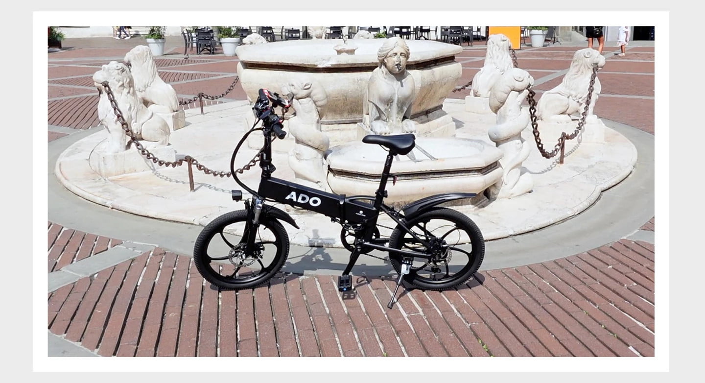 Vélo électrique ADO A20+ devant une fontaine.