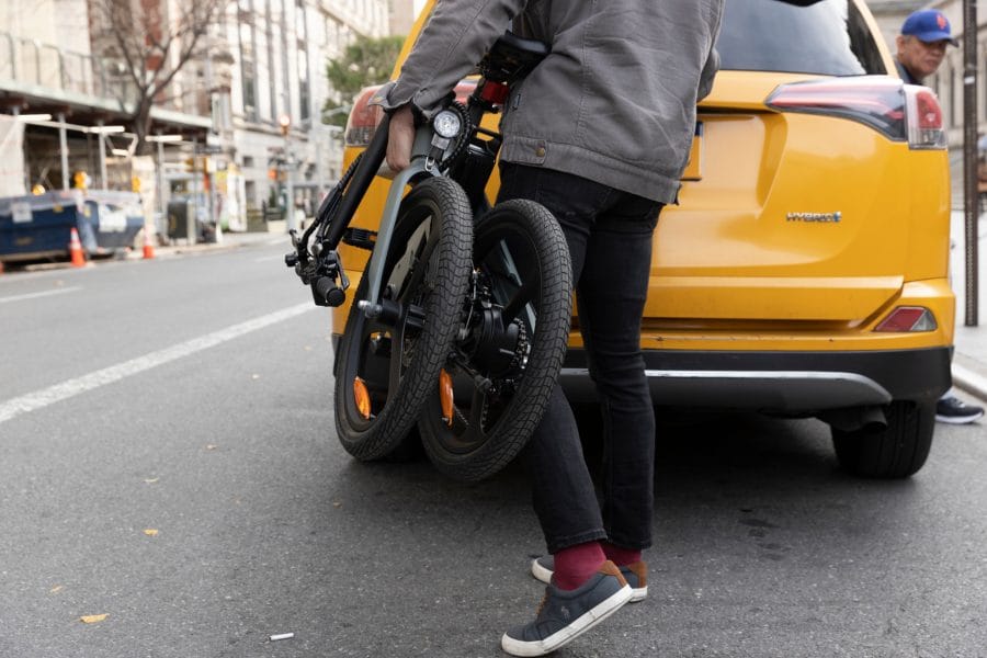 Un homme de DYU T1 porte un vélo électrique plié