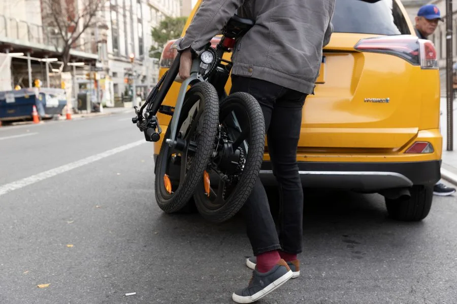 Homem DYU T1 carrega bicicleta elétrica dobrada